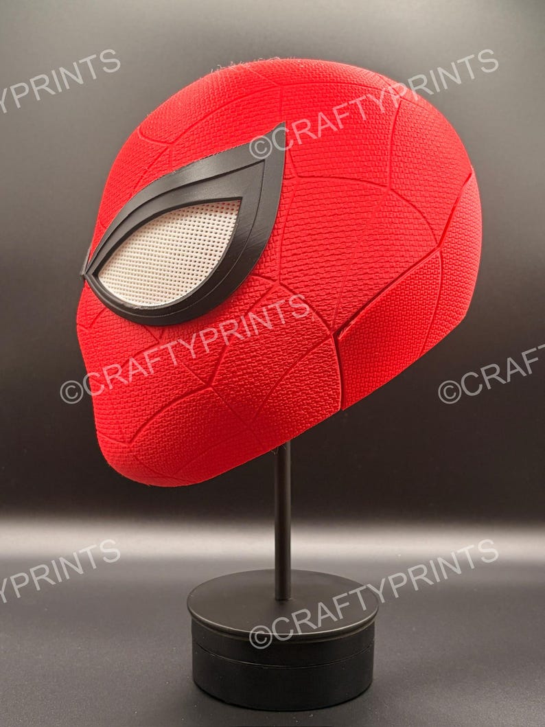 May include: A red textured full-head mask featuring a black web pattern and large white mesh eye lenses with black frames. The mask is displayed on a black stand. The text CRAFTYPRINTS is visible multiple times across the image surface.