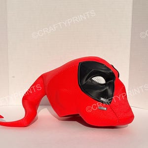 May include: A bright red textured mask featuring a long, curved tail-like extension, a black eye area with white mesh lenses, and two small silver-colored accents near the cheek. The text CRAFTYPRINTS is visible in the background.