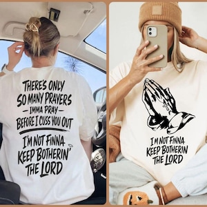 Puede incluir: Una camiseta blanca con texto negro en la parte posterior que dice: There's only so many prayers, imma pray, before I cuss you out, I'm not finna keep botherin' the Lord. El frente presenta un gráfico negro de manos en oración y texto.