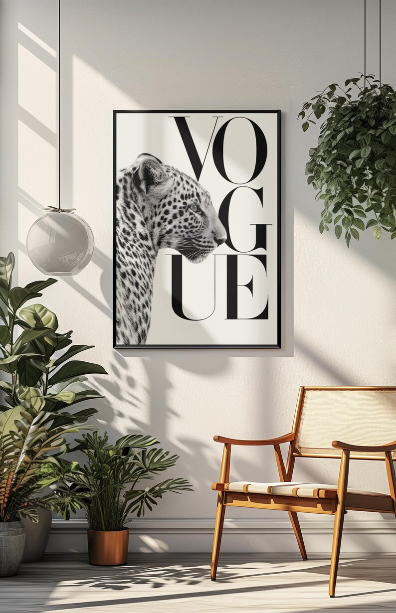 K&ouml;nnte beinhalten: Schwarz-wei&szlig; gerahmter Druck mit einem Leopardenprofil und dem Wort "VOGUE" in gro&szlig;en, schwarzen Buchstaben. Das Bild ist vor einem wei&szlig;en Hintergrund platziert, was einen starken Kontrast erzeugt. Der Druck wird in einem Raum mit Pflanzen und einem Holzstuhl ausgestellt.