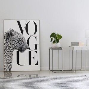 K&ouml;nnte beinhalten: Schwarz-Wei&szlig;-Druck mit einem Leoparden und dem Wort "VOGUE". Zwei Nachttische mit einer Pflanze, B&uuml;chern und einer Lampe. Ein schwarz-wei&szlig; gestreifter Teppich im Vordergrund. Raum mit wei&szlig;en W&auml;nden.
