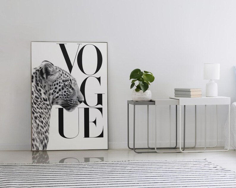 K&ouml;nnte beinhalten: Schwarz-Wei&szlig;-Druck mit einem Leoparden und dem Wort "VOGUE". Zwei Nachttische mit einer Pflanze, B&uuml;chern und einer Lampe. Ein schwarz-wei&szlig; gestreifter Teppich im Vordergrund. Raum mit wei&szlig;en W&auml;nden.