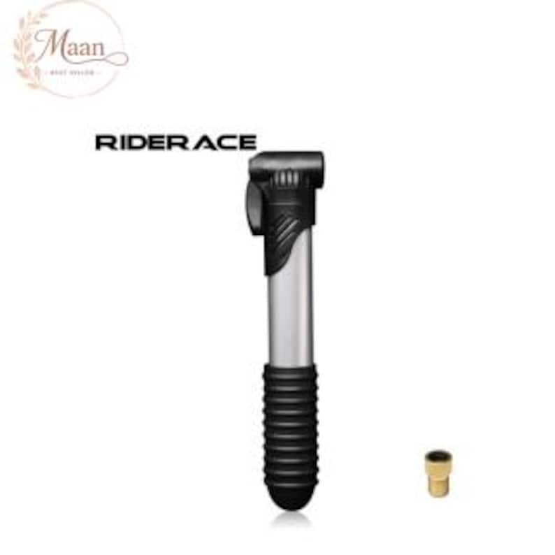 May include: A portable RIDERACE bicycle pump featuring a silver metallic barrel, a black plastic handle with a textured grip, and a black nozzle head. A small brass-colored valve adapter is positioned separately to the right of the pump.