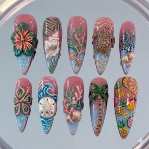 May include: A set of ten stiletto-shaped press-on nails featuring a tropical theme. The designs include 3D raised elements such as a hibiscus flower, seashells, a sea turtle, coral, a palm tree, and various fruits like pineapples and watermelon slices.