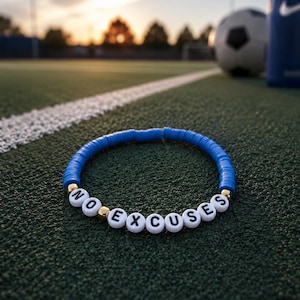 May include: A circular bracelet made of small blue disc-shaped beads, featuring white spherical beads with black letters spelling out the phrase NO EXCUSES, accented by small metallic gold beads interspersed throughout the design.