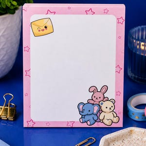 May include: A rectangular notepad with a pink border featuring a pattern of small pink stars. The white centre area displays a winking yellow envelope icon in the top left corner and a cluster of a pink rabbit, blue elephant, and beige bear at the bottom.