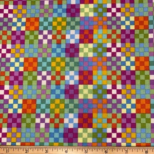 May include: A fabric featuring a repeating grid pattern of small squares in orange, purple, yellow, light blue, and green. A wooden ruler is positioned at the bottom, showing measurements in inches up to 8 inches and centimetres up to 20 cm.