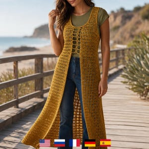 Puede incluir: Un chaleco largo de ganchillo sin mangas en color amarillo mostaza con un patrón vertical de punto abierto y un detalle de cordones central en el pecho. La prenda se lleva sobre una camiseta verde oliva lisa y vaqueros azul oscuro, hasta las rodillas.