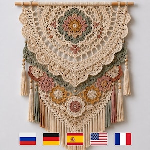 May include: A handcrafted, beige crochet wall hanging with a wooden rod. The design features floral patterns in shades of beige, green, pink, and brown. Decorative tassels and wooden beads add detail to this bohemian-style home decor.