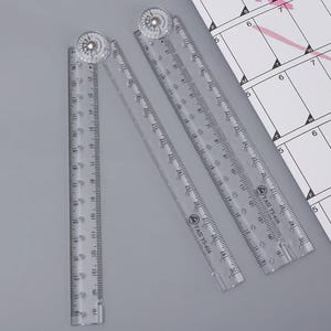 Op de afbeelding: Twee doorzichtige plastic goniometerlinialen met een 360-graden draaibaar gewricht aan de bovenkant. Elke liniaal heeft gedrukte metrische markeringen tot 15 centimeter en imperiale markeringen tot 6 inch, met de merknaam YASI YS-616 erop.