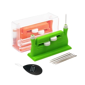 May include: A green plastic sewing machine needle threader tool with white sliding buttons, a clear plastic storage case containing an orange threader, a set of silver sewing needles, and a black teardrop-shaped manual needle threader tool.