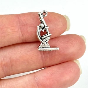 May include: Silver-toned microscope charm with a detailed design. The charm has a loop at the top for attaching to a necklace or bracelet.