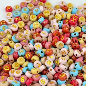 Puede incluir: Un gran surtido de cuentas de letras de plástico de colores. Las cuentas son de varios colores, incluyendo rosa, azul, amarillo, verde y rojo. Cada cuenta tiene una letra del alfabeto impresa.