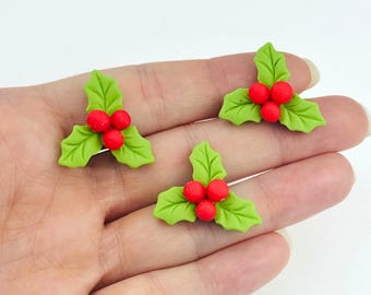 Könnte beinhalten: Drei grüne Mistelzweig-Ornamente mit roten Beeren. Jedes Ornament hat drei Blätter und drei Beeren.