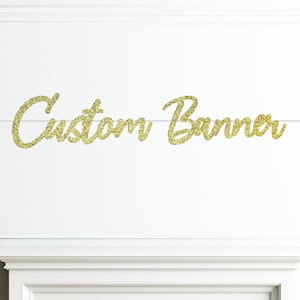 May include: Gold glitter banner with the text "Custom Banner" hanging on a white wall.
