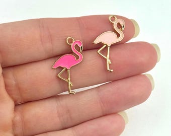 May include: Two gold-tone flamingo charms with pink enamel. The flamingo on the left is a darker pink, while the flamingo on the right is a lighter pink.