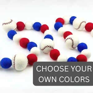 May include: A decorative garland with white baseballs and brown stitching, alongside red, white, and blue felt balls. The text "CHOOSE YOUR OWN COLORS" is displayed on a grey background.