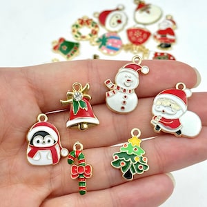 May include: Assortment of gold-tone Christmas charm pendants featuring various holiday themes, including a snowman, Santa Claus, a penguin, a candy cane, a bell, a Christmas tree, and a wreath.