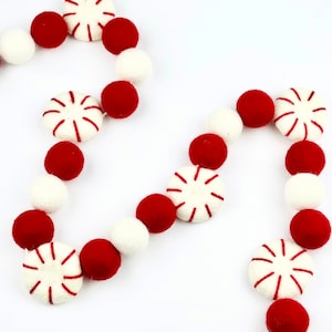 May include: A festive garland made of red and white felt balls, with peppermint candy designs. The garland is perfect for decorating for the holidays.