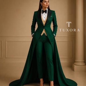 May include: A dark green tuxedo suit featuring a long, floor-length train attached to the jacket, a tan vest, a white button-down shirt, and a black bow tie. The text TUXORA is visible on the right side of the image with a logo above it.