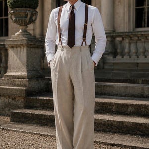 May include: A white long-sleeved dress shirt with a dark brown necktie and brown suspenders paired with high-waisted beige trousers featuring double pleats and cuffed hems. The word TUXORA is printed in the upper left corner of the image.