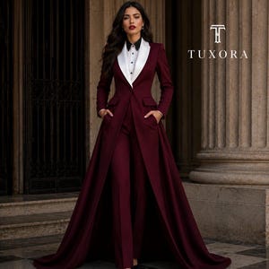 May include: A deep burgundy long-line blazer with a white shawl lapel and matching trousers, worn over a white button-down shirt with a black collar. The blazer features a floor-length skirt overlay and side pockets. The text TUXORA is visible.