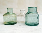 Vintage ink wells. Collection of three glass ink bottles, clear, blue and green. Circa 1900 or earlier.