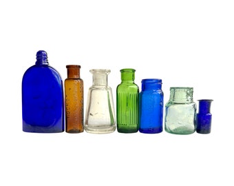 A collection of 7 small glass bottles of different shapes. Collectable vintage glass.