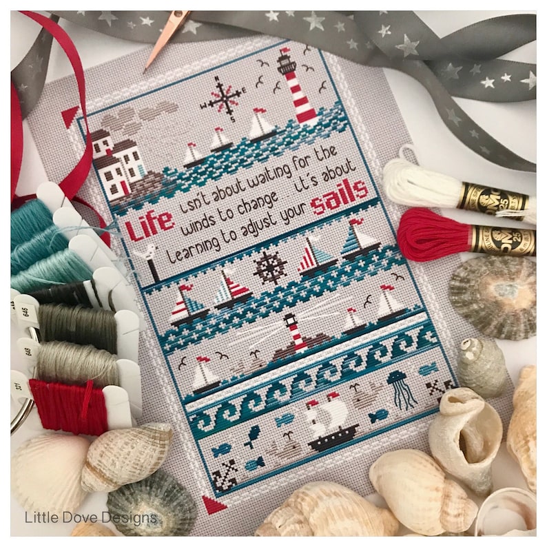 May include: Cross-stitch design with a nautical theme, featuring sailboats, lighthouses, and the quote "Life isn't about waiting for the winds to change...it's about learning to adjust your sails." The design incorporates teal, red, and white colors, with seashells and embroidery floss in the background.