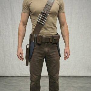 Puede incluir: Un cintur&oacute;n utilitario y una bandolera de cuero marr&oacute;n con cilindros y bolsas plateadas. El cintur&oacute;n se usa con pantalones marrones y una camiseta beige. Una funda est&aacute; sujeta al cintur&oacute;n.