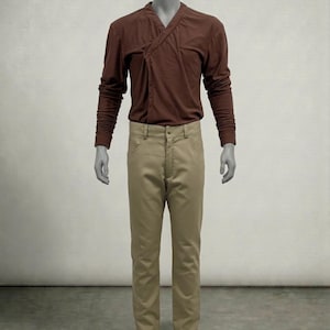 Puede incluir: Una camisa marr&oacute;n de manga larga con cuello cruzado y pantalones color beige. La camisa tiene un dise&ntilde;o &uacute;nico y los pantalones son de color neutro. El conjunto se exhibe en un maniqu&iacute;.