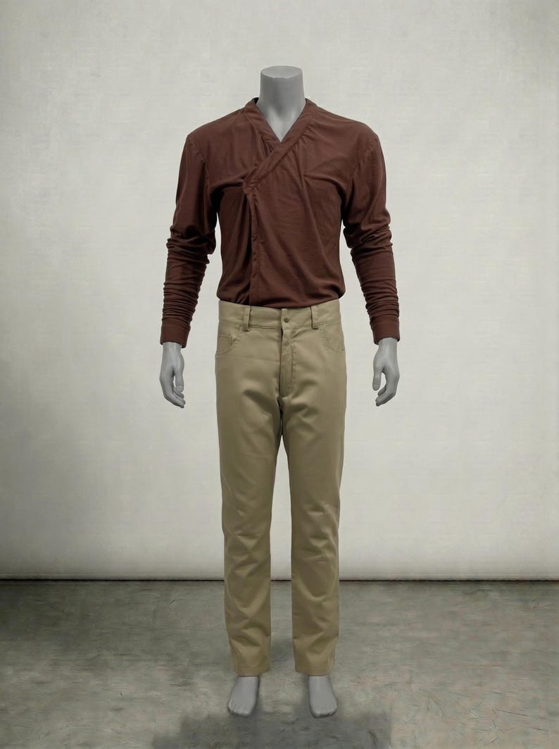Puede incluir: Una camisa marr&oacute;n de manga larga con cuello cruzado y pantalones color beige. La camisa tiene un dise&ntilde;o &uacute;nico y los pantalones son de color neutro. El conjunto se exhibe en un maniqu&iacute;.