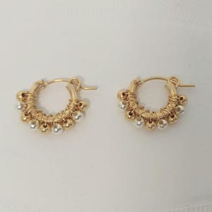 Puede incluir: Un par de pendientes de aro de oro con cuentas de plata que cuelgan de los aros.