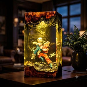 May include: A rectangular resin lamp featuring a wooden base and top with a natural grain. Inside the clear resin, two anime figures are captured in a dynamic combat pose, illuminated by a warm yellow light that creates a glowing effect.