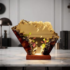 May include: A decorative resin lamp featuring a translucent amber-toned panel with embedded miniature coral reef elements, colorful fish, and jellyfish figures, set upon a rectangular wooden base with an integrated light source at the bottom.
