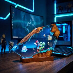 May include: A decorative resin and wood lamp featuring a miniature Mario riding Yoshi, a Boo ghost, a question mark block, a star, and coins. The scene is encased in clear resin with natural wood edges, illuminated by a blue light on a wooden base.