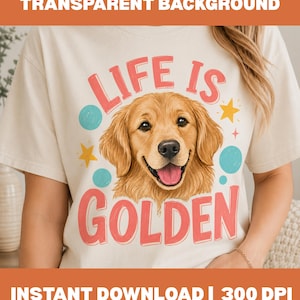 Puede incluir: Una camiseta color crema con un gráfico de un perro golden retriever con la lengua fuera. El texto "LIFE IS GOLDEN" está impreso en rosa encima y debajo del perro, acentuado por círculos azul claro y estrellas amarillas en la parte frontal.