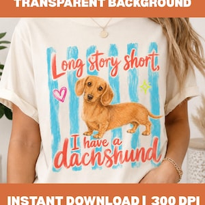 Puede incluir: Una camiseta de color crema con un gráfico de un perro salchicha marrón centrado sobre pinceladas azules verticales. El texto dice Long story short, I have a dachshund en letra roja, junto a un corazón rosa y un icono de estrella amarilla.