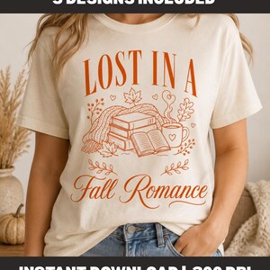 以下が含まれることがあります： LOST IN A Fall Romanceというオレンジ色のグラフィックテキストがプリントされたクリーム色のTシャツ。デザインには、本の山、開いた本、湯気の立つマグカップ、ニットのスカーフ、小さなハートが描かれた秋の葉のイラストが含まれています。