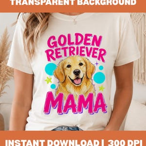 Puede incluir: Una camiseta de manga corta color crema con un gráfico de un perro Golden Retriever. El texto "GOLDEN RETRIEVER MAMA" aparece en letras rosa brillante. El diseño incluye círculos azules y estrellas verde lima alrededor del perro.