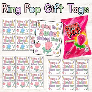 May include: A collection of printable gift tags featuring the text Ring in a Sweet School Year, illustrated with a Ring Pop candy, a pencil, a crayon, and an apple. A single strawberry Ring Pop candy in a pink wrapper is displayed next to the tags.