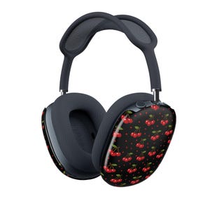 Op de afbeelding: Over-ear hoofdtelefoon met een donkergrijze hoofdband en mesh oorkussens. De buitenste oorschelpen hebben een zwarte achtergrond met een patroon van kleine rode kersen en kleine witte stippen, wat een visueel contrast vormt met het grijze frame.