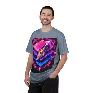 May include: A light blue t-shirt featuring a vibrant graphic. The graphic showcases a gold pen nib atop stacked, glowing geometric shapes in pink, purple, and blue, with a black background. The design has a neon, digital art style.