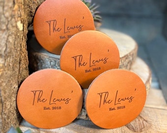 Könnte beinhalten: Vier braune Lederuntersetzer mit dem eingravierten Text "The Lewis' Est. 2018" auf jedem.