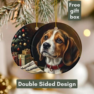 May include: Circular ceramic Christmas decoration featuring a beagle dog with brown, white, and black fur, wearing a red collar. The reverse side shows a Christmas tree and wrapped gifts. The ornament hangs from a gold string. Text reads "Double Sided Design".
