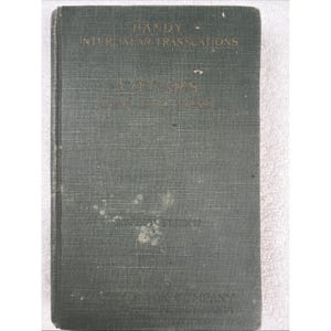 May include: A dark green hardcover book titled Handy Interlinear Translations Caesar's Civil War. The front cover features faded gold lettering and shows signs of wear, including light surface scuffing and small white spots on the fabric texture.