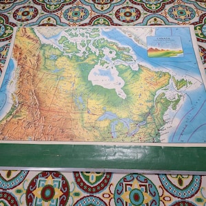 May include: A vintage map of Canada with a green and brown color scheme. The map shows the provinces and territories of Canada, as well as major cities and rivers. The map is titled "Canada" and is surrounded by a green border.