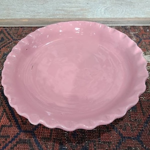 May include: A pink ceramic pie plate with a scalloped edge.