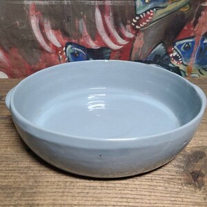 May include: A light blue ceramic baking dish with a rounded rim and a smooth, glazed interior. The dish is empty and appears to be new.