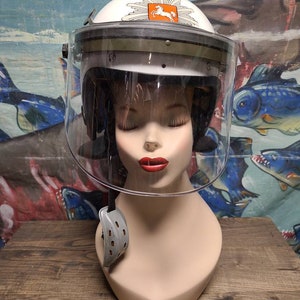May include: White motorcycle helmet with a clear visor and a black and orange emblem with a horse on it.